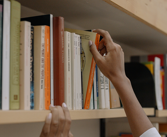 Hand reaching a book from the shelf